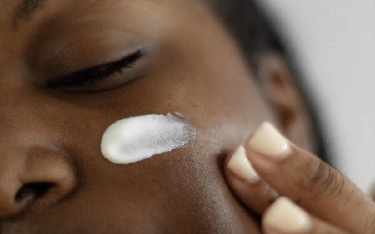 Close-up of brightening cream being applied to woman with clear, even-toned skin