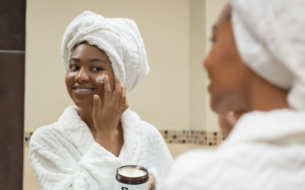 Calm self-care moment, woman in white robe applying gentle skincare to face