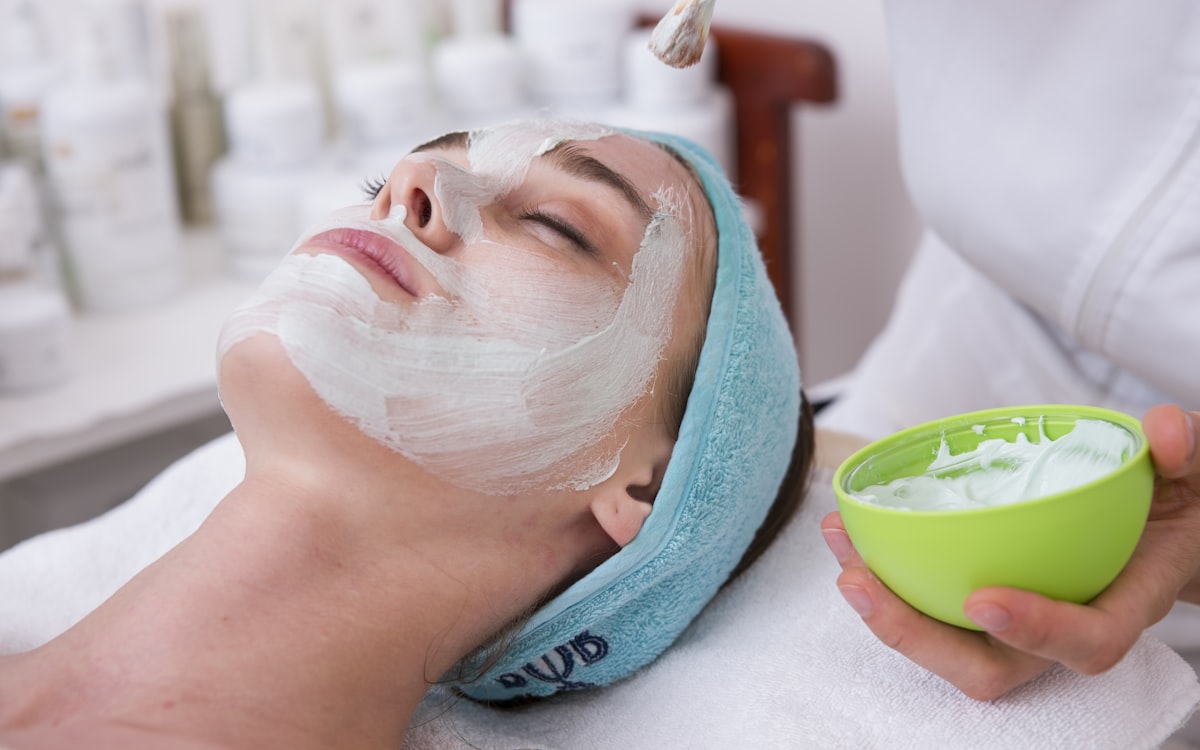Woman receiving a calming spa facial with white mask and headband